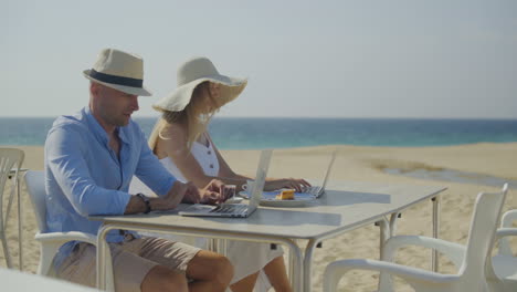 Paar-Benutzt-Gemeinsam-Laptops-Am-Strand