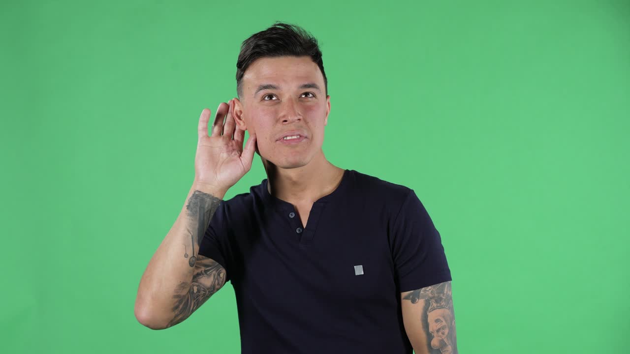 retrato de un joven guapo está sosteniendo la mano cerca de la oreja tratando de escuchar noticias interesantes expresando concepto de comunicación y chismes. pantalla verde
