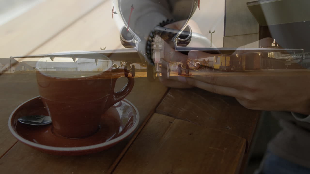 테이블 위에 스마트폰과 커피 컵을 들고 있는 사람 위에서 애니메이션을 찍는 비행기