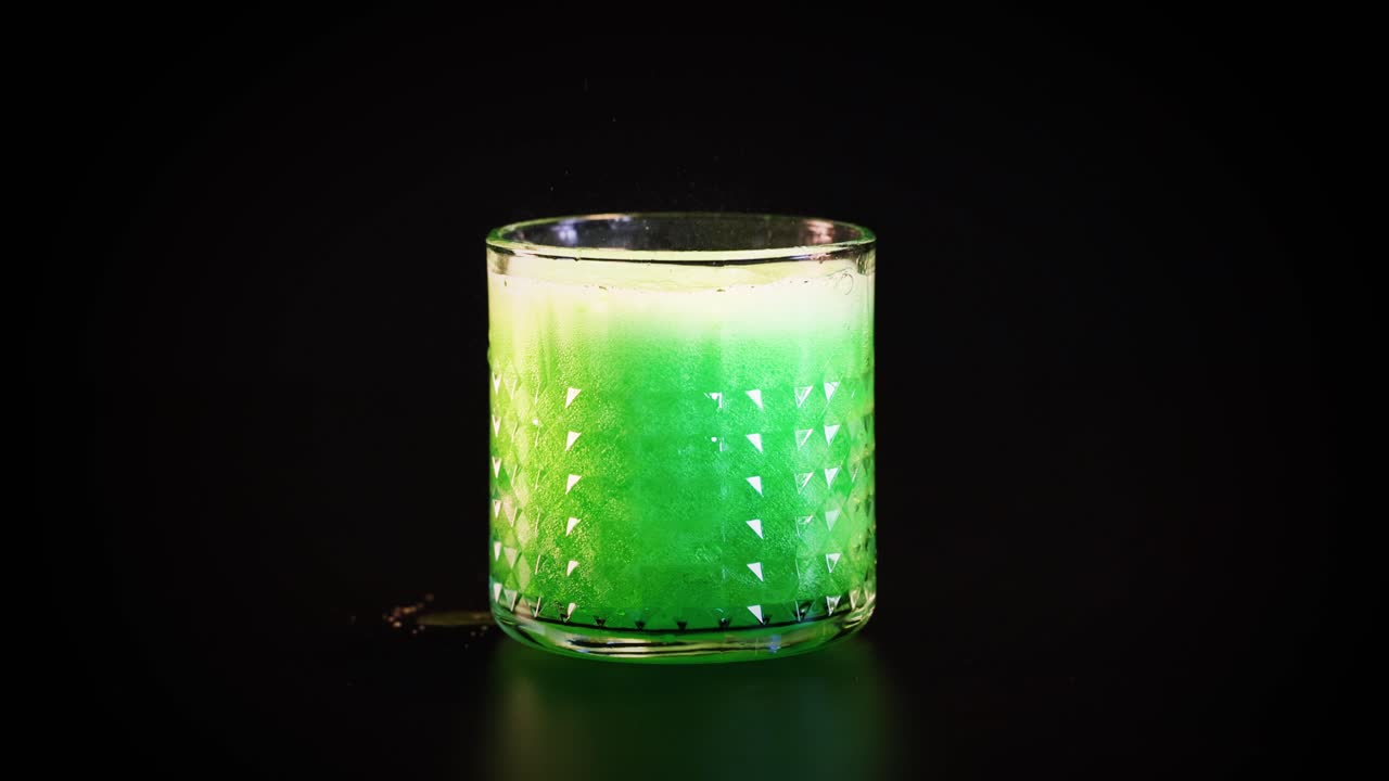 bebida verde vertida en un vaso, formando burbujas