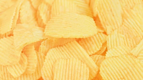 chips de patata de color amarillo ondulado en bucle giratorio en primer plano de fondo de cuadro completo
