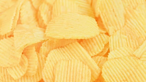 looped spinning yellow wavy potato chips full frame close-up background