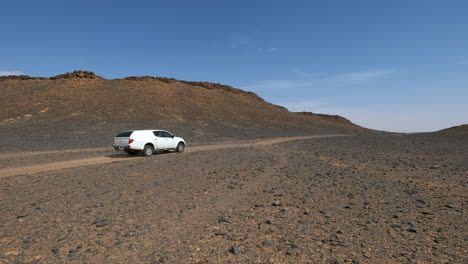 pickup truck driving by in a hot sahara desert in morocco