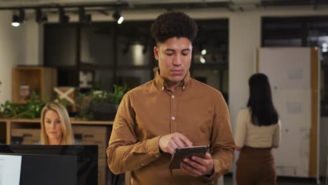 Video-Eines-Fokussierten-Gemischtrassigen-Mannes-Mit-Tablet,-Der-Spät-Im-Büro-Arbeitet