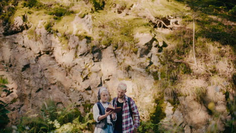 male and female tourists reading book against rocks