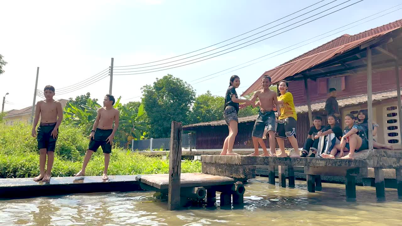 Children playfully jump into canal water