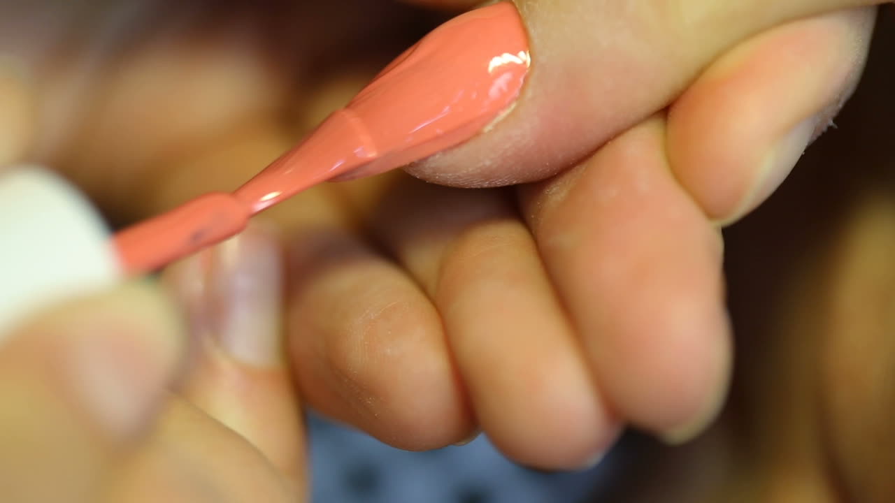 Female hands painted nails. Woman paint nails with lacquer in the beauty salon