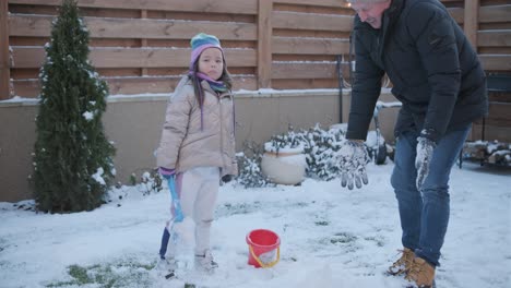 grandfather and granddaughter having fun in the snow