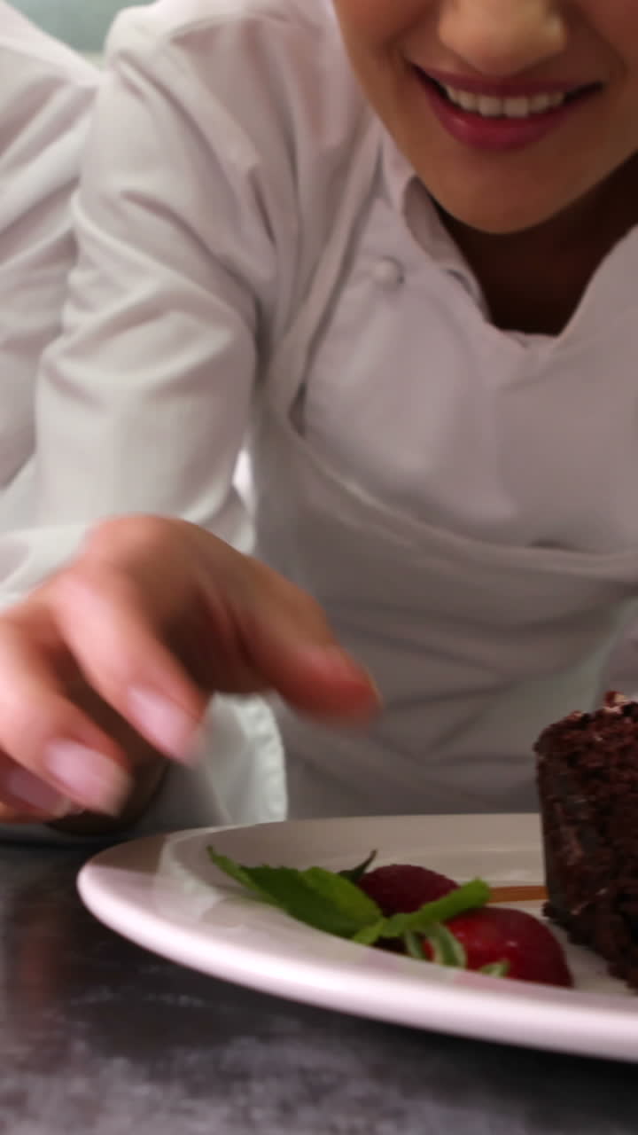 línea de chefs adornando platos de postre con hojas de menta y fresas