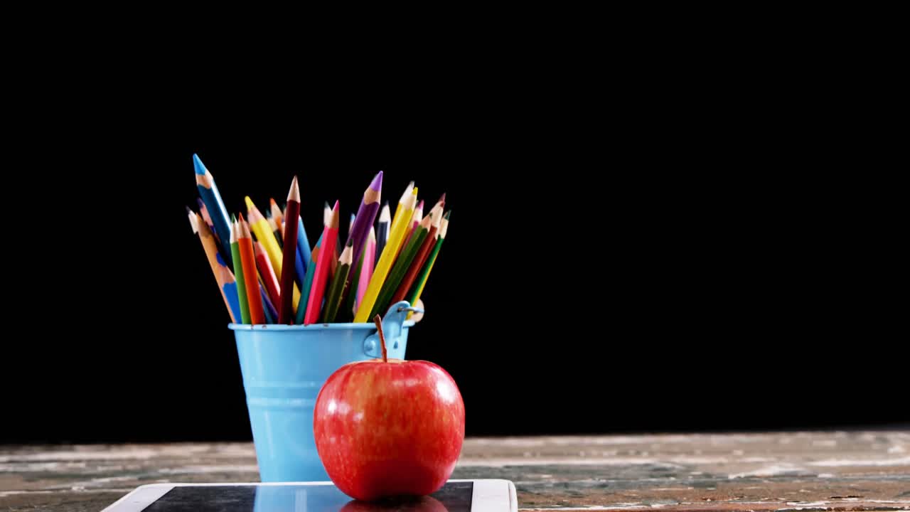 manzana en una tableta digital con lápices de color en la mesa