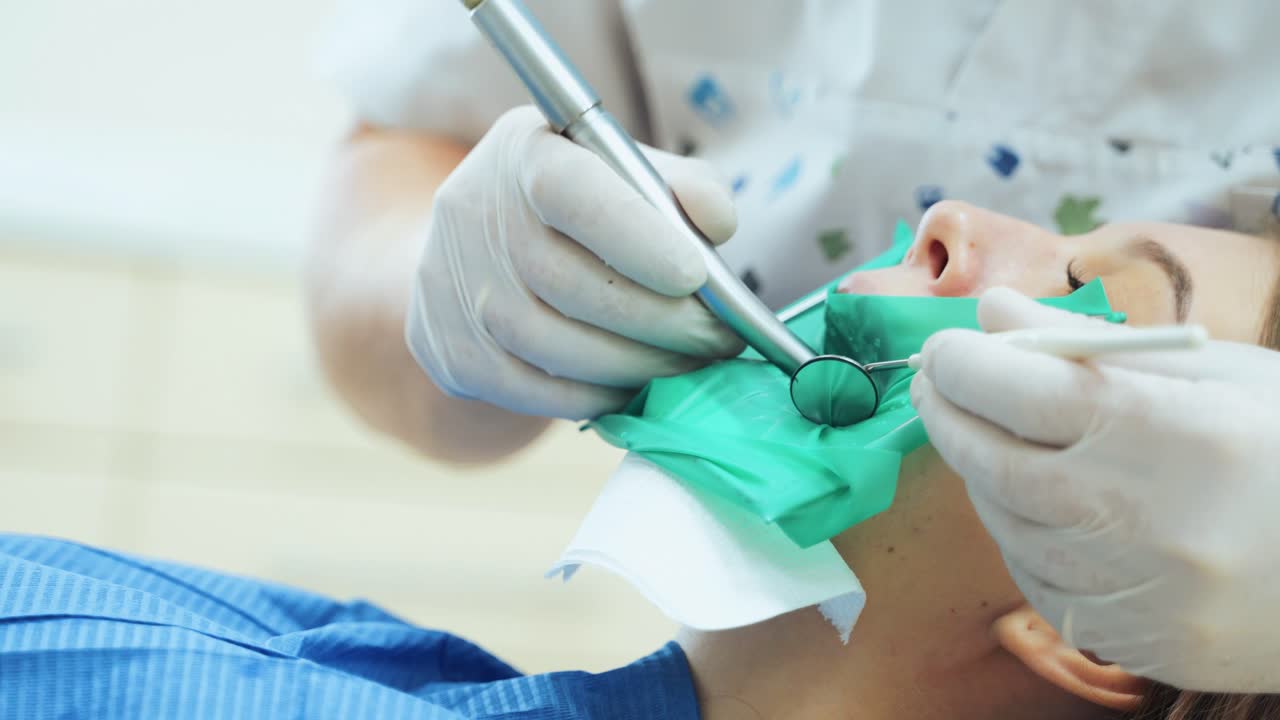 A doctor in rubber gloves with a dental drill is treating teeth. Visit to the dental clinic