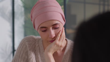 close up of serious young woman patient wearing headscarf undergoing chemotherapy treatment for breast cancer meeting with oncologist or doctor in hospital