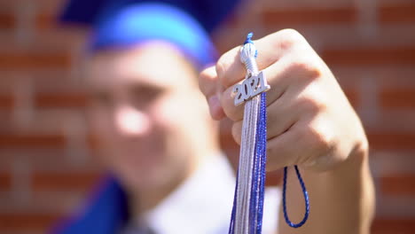 El-Primer-Plano-De-Un-Graduado-Masculino-Feliz-Sostiene-Su-Borla-De-Graduación-De-2021