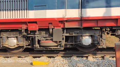 vista lateral de vagones de pasajeros en el ferrocarril indio que corren por la vía