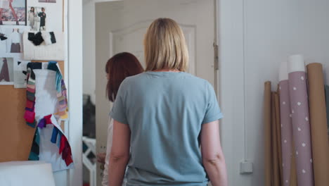 Fashion designers walk away from design board filled with fabric samples and sketches, closing door behind them in bright fashion studio, leaving after brainstorming session