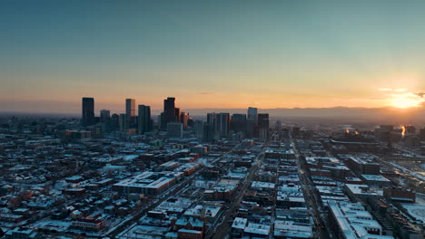 sunset aerial view of snow covered denver skyline in winter