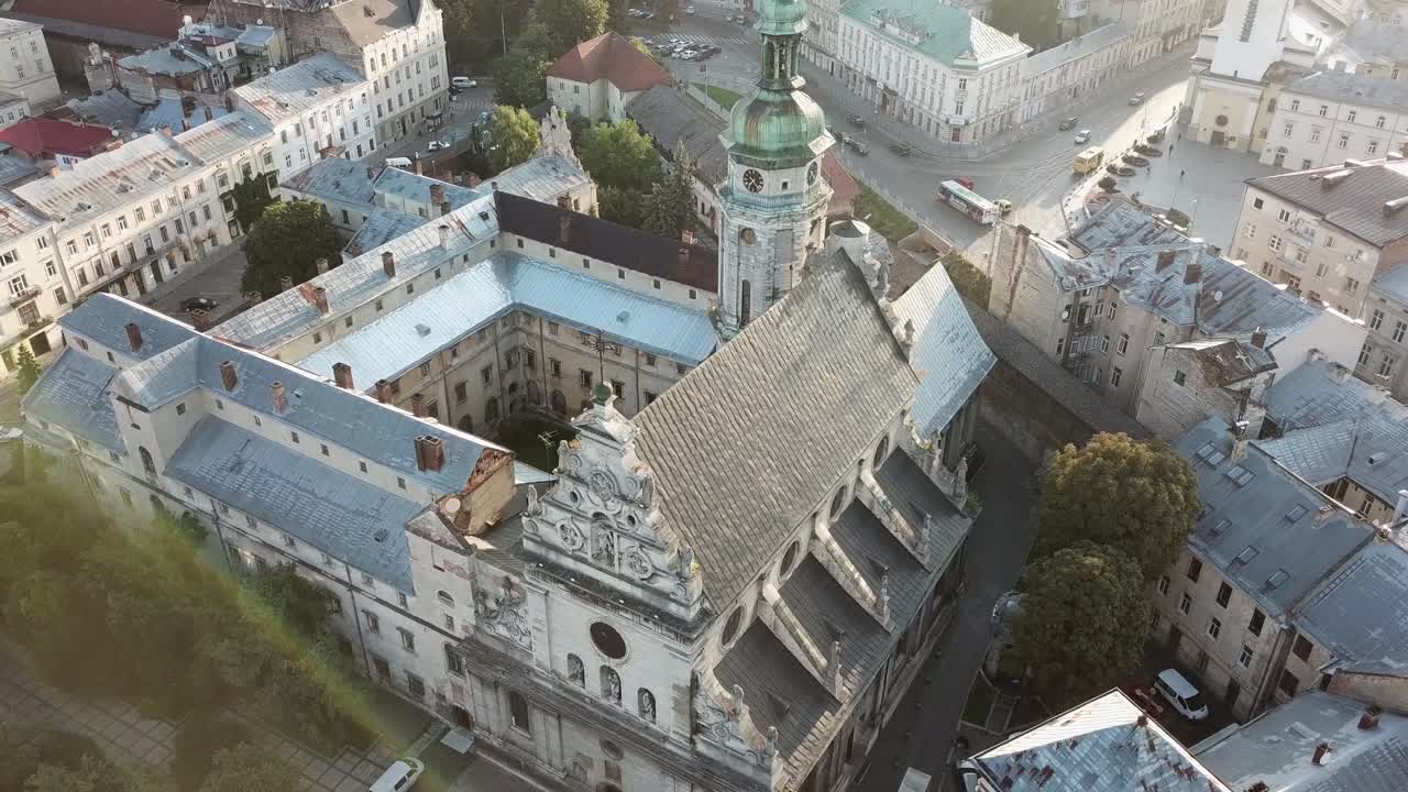 Ukraine, Lviv, Bernardin Church, Drone footage turns around the beautiful historical building from left to right with the sun light shinning, traffic, streets and trees around the building is visible.