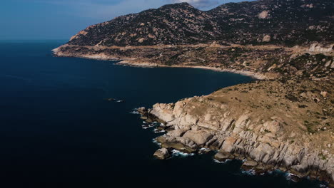 Majestic-Mui-Dinh-bay-coastline-with-mountain-range-behind-in-Vietnam,-aerial-view