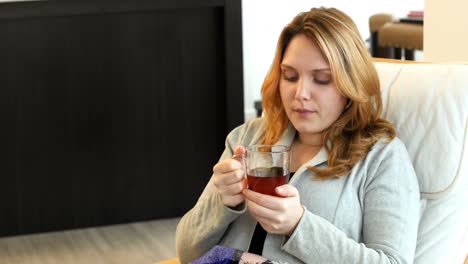 mujer sentada en el sofá y bebiendo café