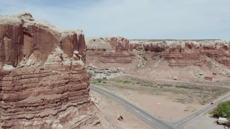 sandstone buttes and red rock formations by desert road in southwest desert of utah - aerial