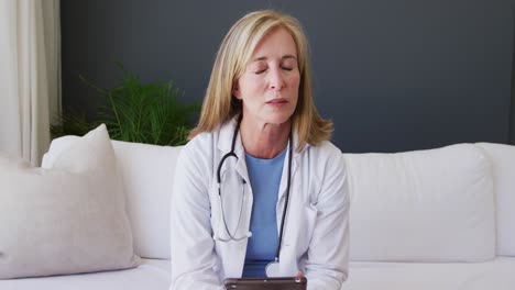 reassuring caucasian senior female doctor wearing lab coat and stethoscope talking to camera