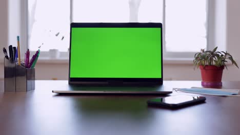 green screen laptop computer sitting on a home work desk.