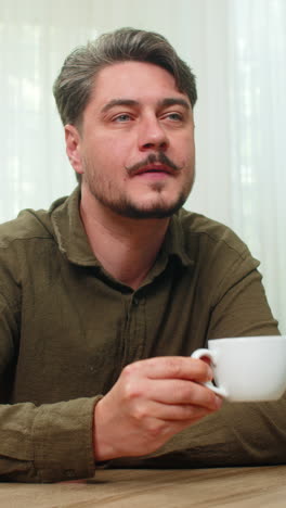 middleaged man enjoying peaceful coffee moment sipping warm beverage calmly smiling at table desk