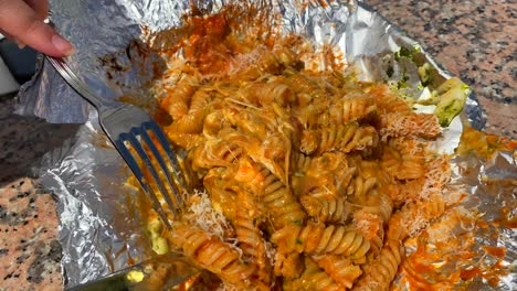 pasta muy quesada con pesto verde y rojo, mezclando pasta con un tenedor y un cuchillo, plato italiano tradicional, famosa pasta en puerto banus marbella, tiro de 4k