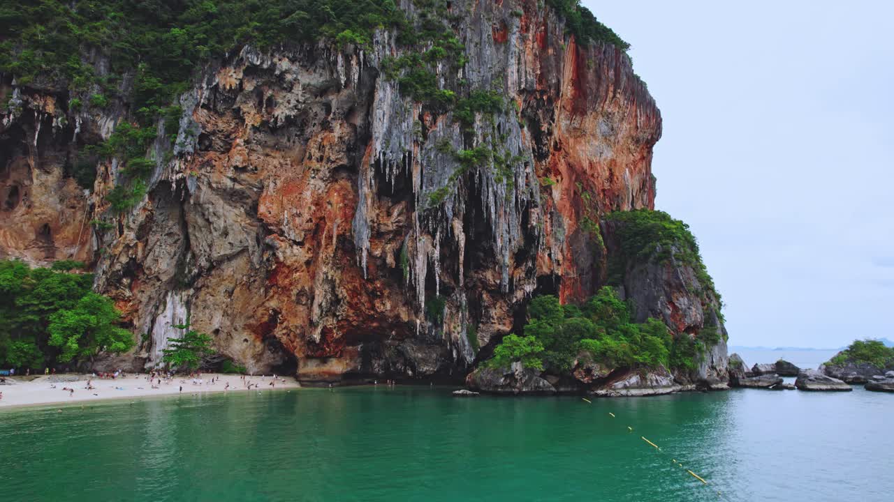 Spiaggia di Phra Nang a Railay con ripide scogliere calcaree da un drone aereo che si inclina verso l'alto sulle rocce