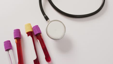 Video-of-close-up-of-stethoscope-with-test-tubes-on-pink-background