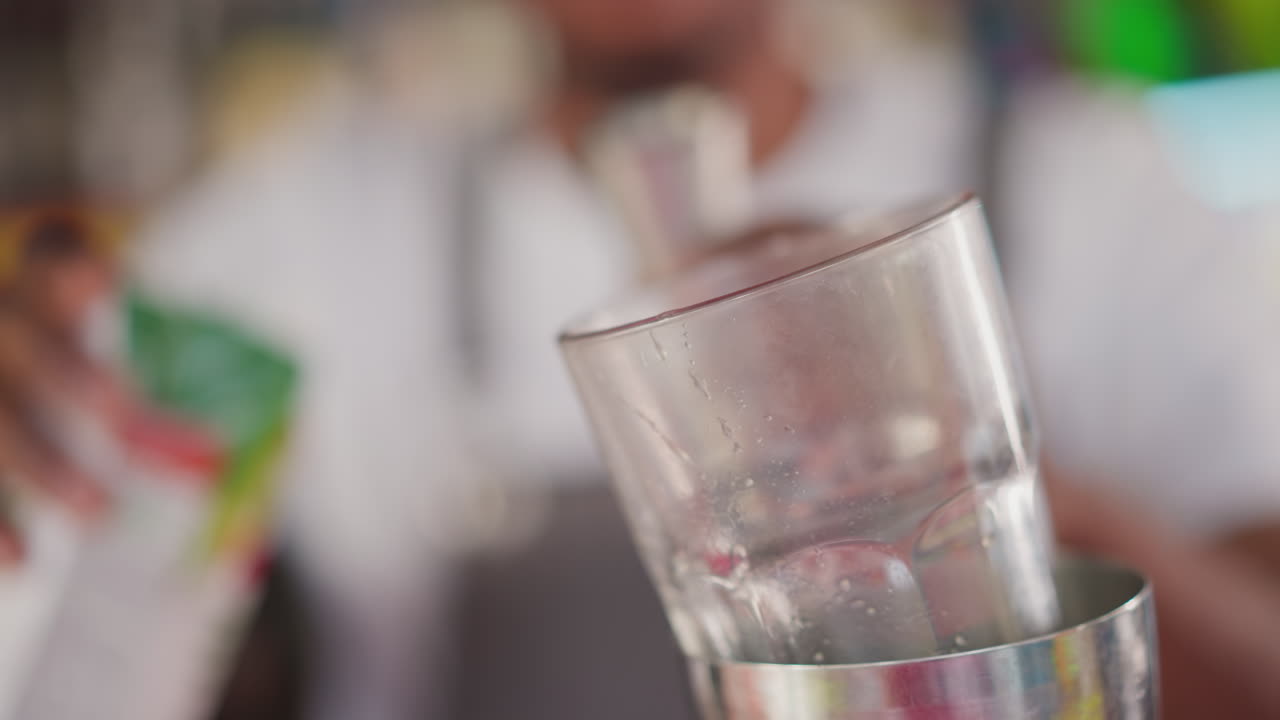 술집 주인이 술집에서 유리잔에 주스를 부어주고, 검은색 술집주인이 클럽에서 맛있는 테일의 재료를 추가하고, 술집 관리자가 손님 음료를 준비합니다.