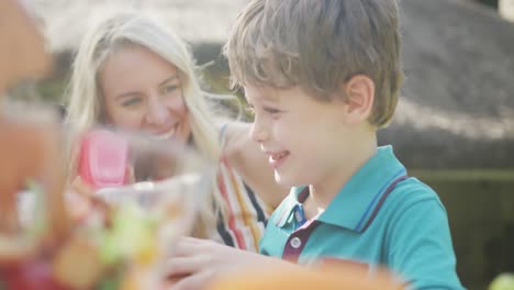 happy caucasian mother and son having dinner and talking in garden