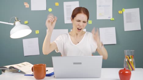 woman looks at laptop and rejoices.