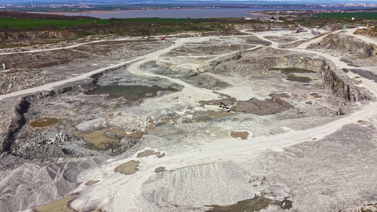 Cava di granito con terreno roccioso e macchinari in funzione vicino a un paesaggio verde durante le ore diurne.