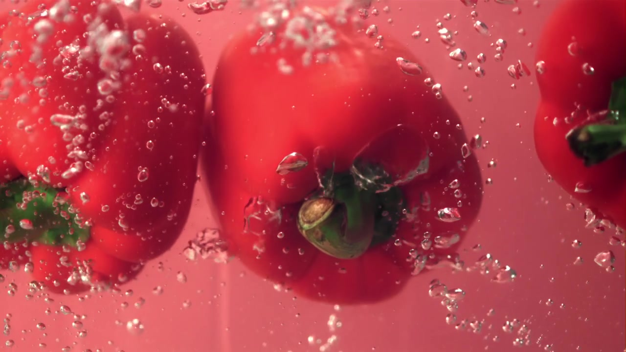Fresh Red Bell Peppers Submerged in Water with Rising Bubbles