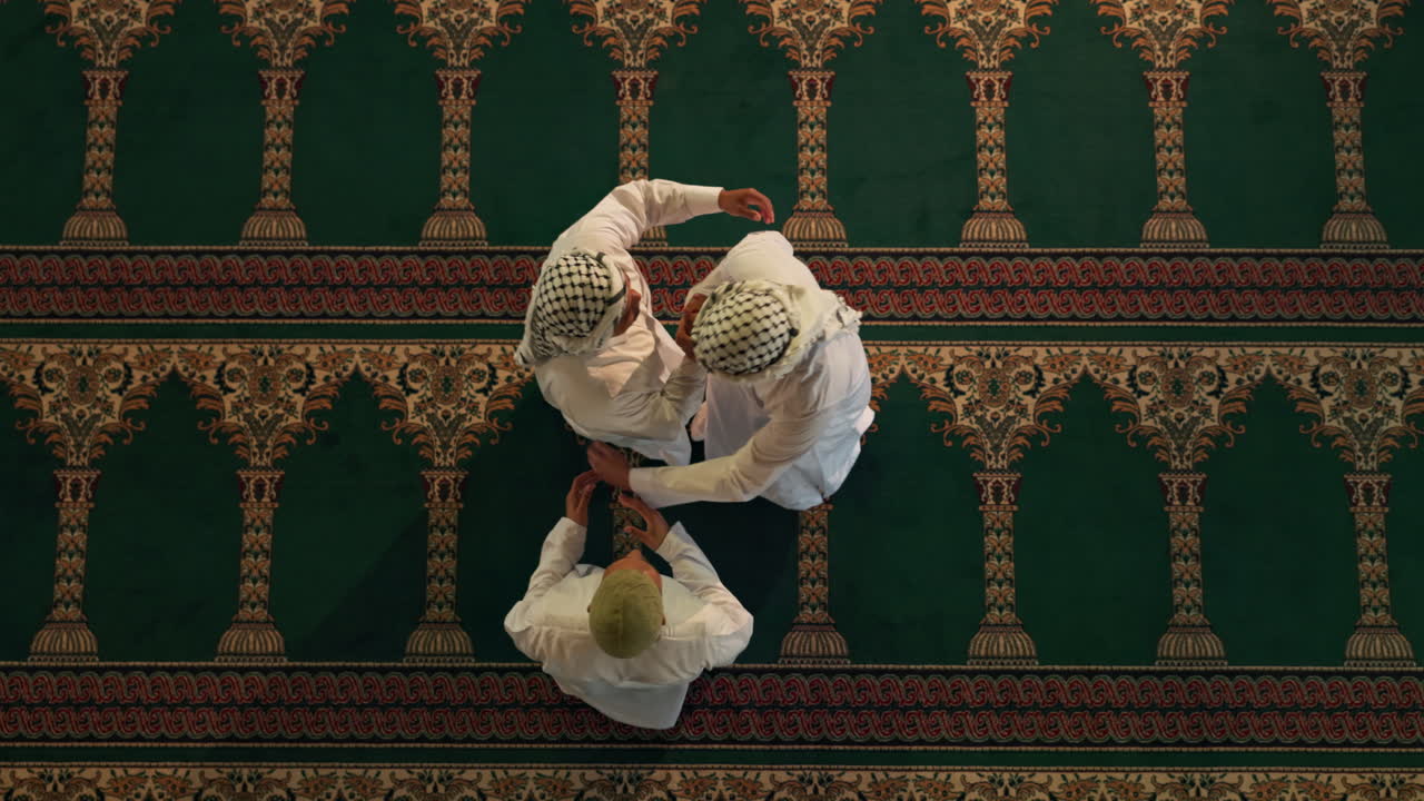 Three men in traditional Islamic clothing on a green carpet