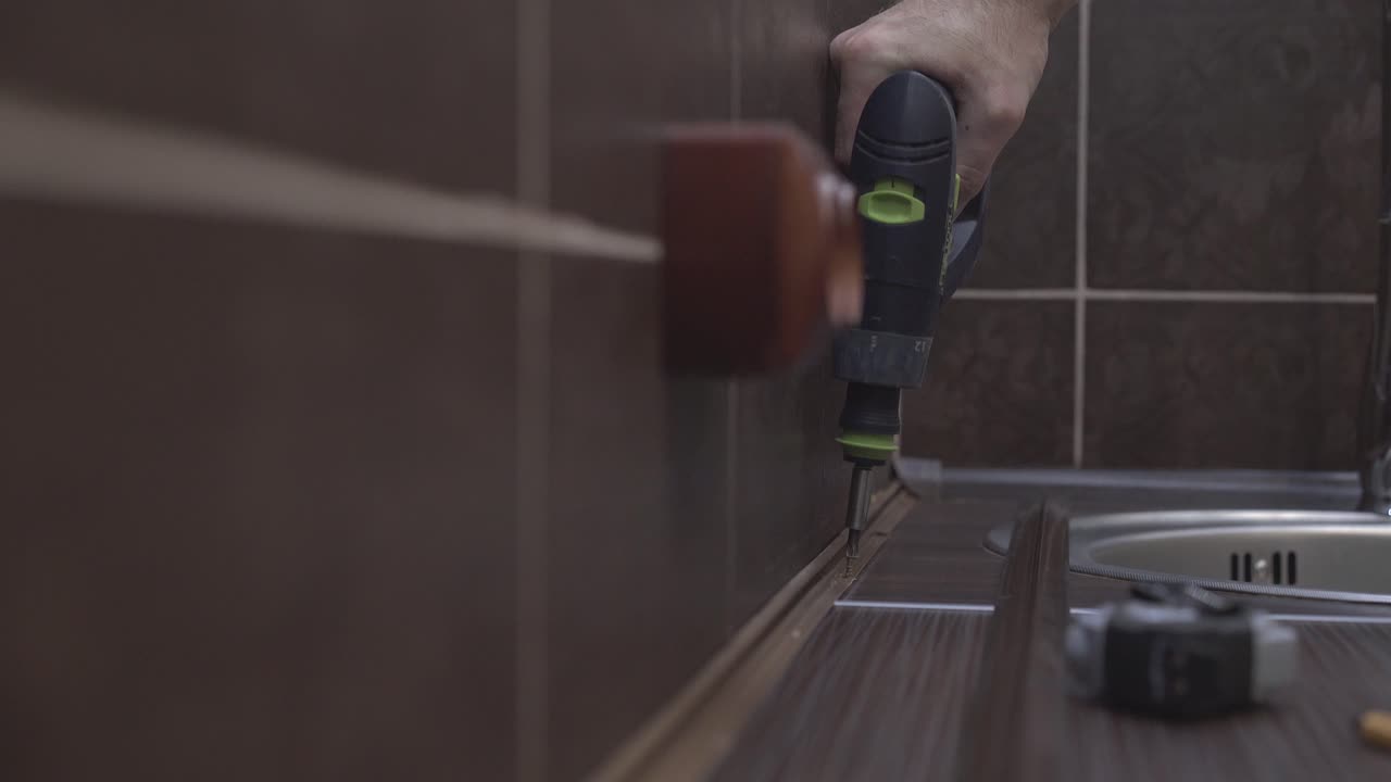 el maestro que produce muebles fija el pedestal a la superficie de la mesa usando un destornillador