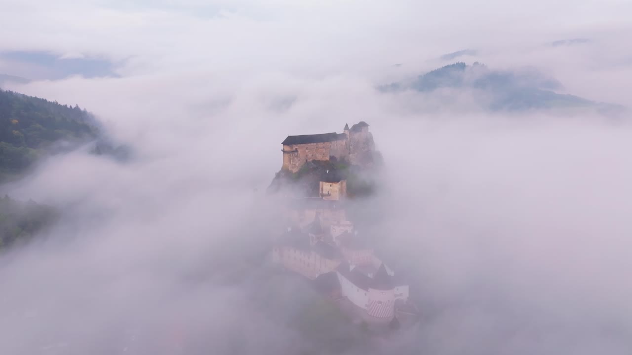 Aerial panorama of Orava Castle resting above the foggy countryside