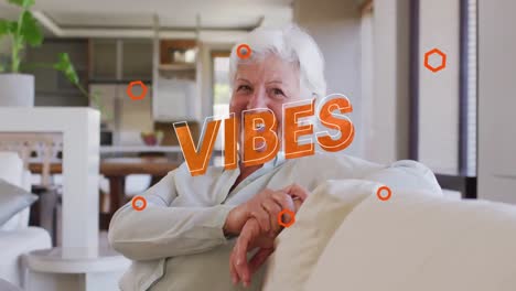 Animation-Von-Vibes-In-Orange-über-Einem-Glücklichen-Kaukasischen-Senior,-Der-Lachend-Im-Wohnzimmer-Sitzt