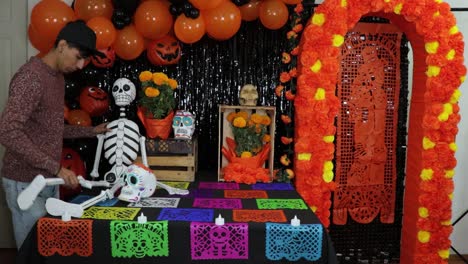 hombre latino poniendo un esqueleto de plástico en el altar decorado del día de los muertos