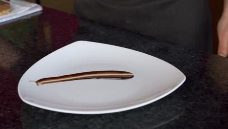 close-up shot of a chef spreading chocolate sauce over a plate for presentation