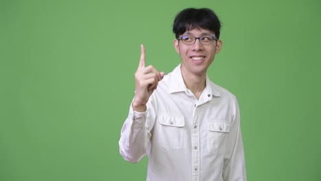 young happy asian businessman pointing up and thinking