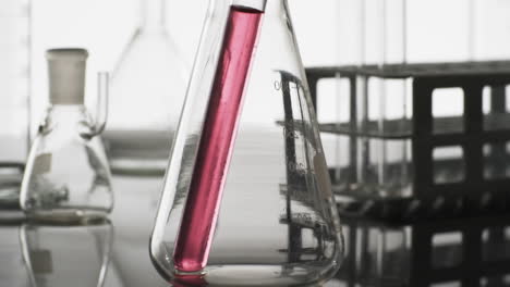 vídeo de un tubo de ensayo de laboratorio de vidrio con líquido rosado en un vaso con espacio de copia sobre fondo blanco
