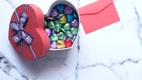 heart-shaped gift box filled with colorful chocolates and red envelope