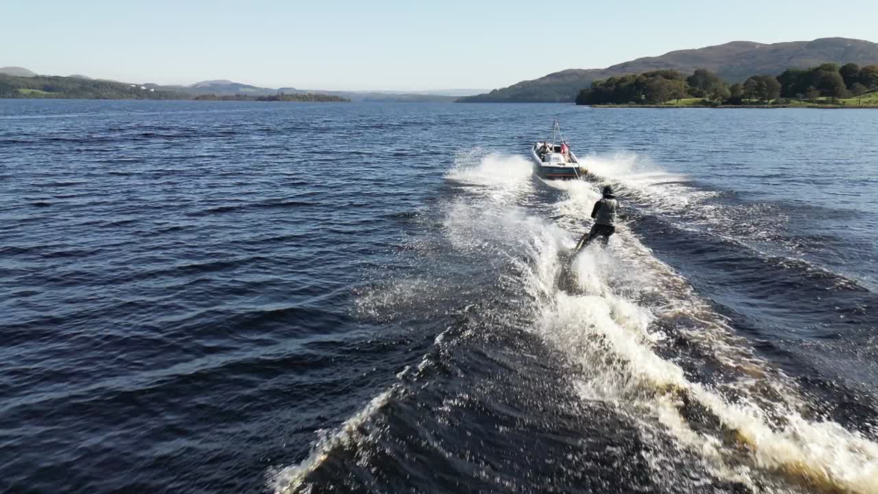 Water skiing fun, boat towing skier on open water, slow motion video