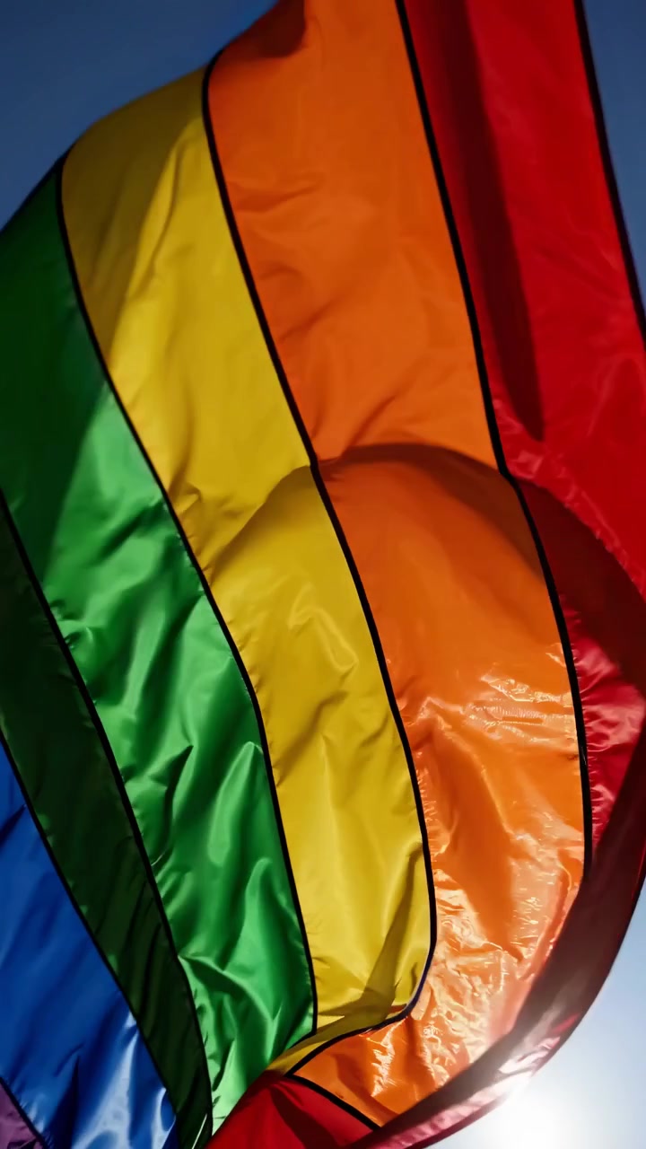 Eloisa sateenkaari-pride-lippu liehumassa kirkasta sinistä taivasta vasten