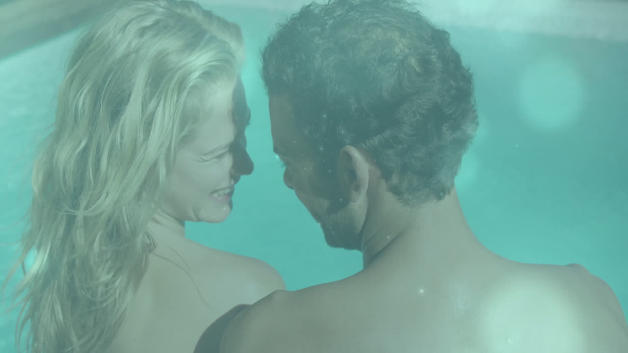 In swimming pool, couple relaxing and embracing, sharing joyful animation together