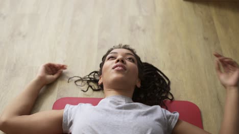 young african american female athlete working out in the living room, fall tired on mat