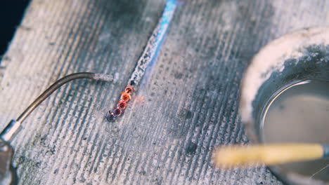 jeweler welds links of chain on fireproof sheet close view