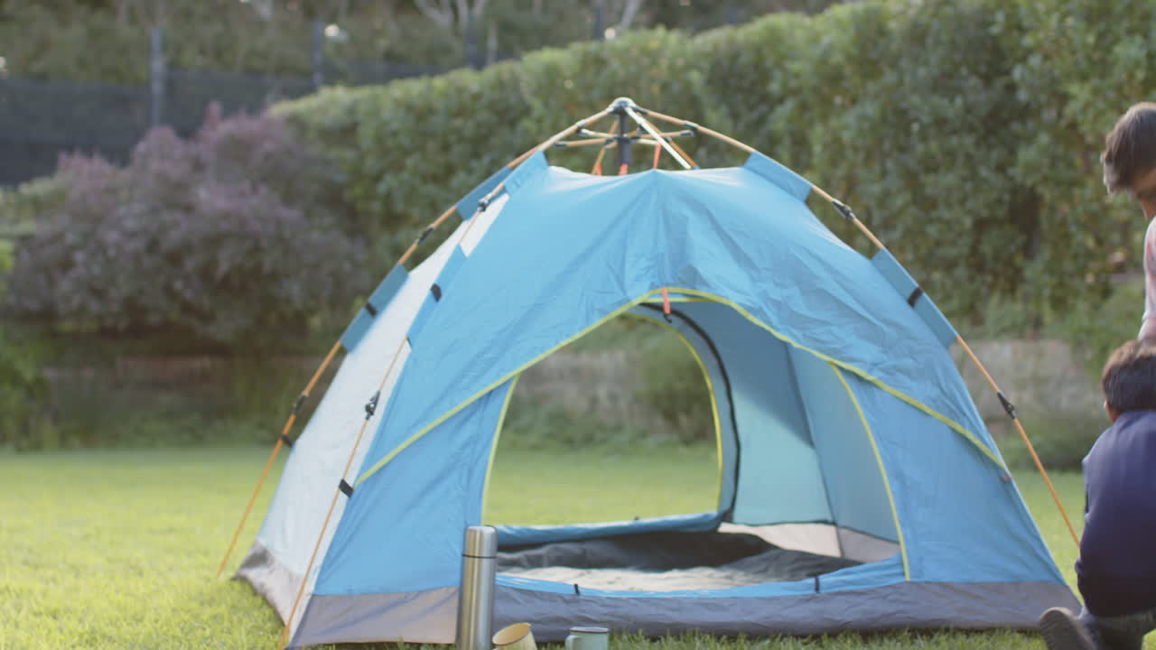 Setting up blue tent, Indian father and young son enjoying outdoor camping